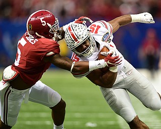 NEW ORLEANS, LOUISIANA - JANUARY 1, 2015: Ezekiel Elliott #15 of Ohio State runs the ball down the sideline while running through a tackle from Cyrus Jones #5 of Alabama during the 2nd quarter of Thursday nights game at the Superdome. (Photo by David Dermer/Youngstown Vindicator)