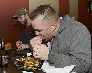 Katie Rickman | The Vindicator.Jim Murphy eats his burger at V2 with fellow Burger Guyz on Dec. 30, 2014.