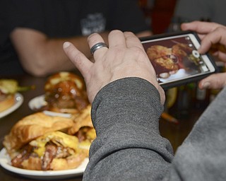 Katie Rickman | The Vindicator.One of the burger guys takes a photo of burgers at V2 during their visit to the the Youngstown burger joint on Dec. 30, 2014.