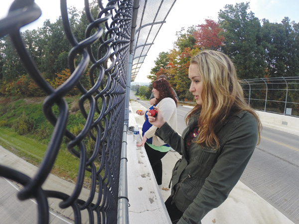 Kaely Hawkins, left, and Nicolette Pizzuto, students at Youngstown State University and NewsOutlet interns, use clickers to count cars passing below the Route 711 overpass. They also were counting the number of drivers using cellphones.