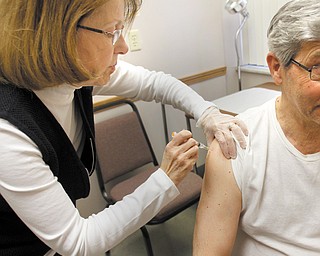 Brenda Christensen , a registered nurse, administers the flu vaccine to a client during a Mahoning County Board of Health clinic Tuesday in Austintown. Mahoning and Trumbull counties have been hard-hit by the flu virus, county and state health officials said.