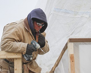        ROBERT K. YOSAY  | THE VINDICATOR..Don Loveless uses Carharts, Hoody's   and layers to keep warm as he puts up a plastic curtain around a job AEF Designs as they remodel Huntington Woods Mall