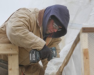        ROBERT K. YOSAY  | THE VINDICATOR..Don Loveless uses Carharts, Hoody's   and layers to keep warm as he puts up a plastic curtain around a job AEF Designs as they remodel Huntington Woods Mall