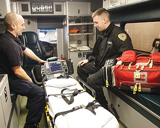 Brandon Wirtz , left, an Austintown firefighter and paramedic, and Ryan Caron , a Lane LifeTrans paramedic, check their gear before starting their shift at Austintown Fire Station No. 1 on Wednesday. A collaboration between Lane and the township fire department is now a year old and has cut down response times in Austintown.