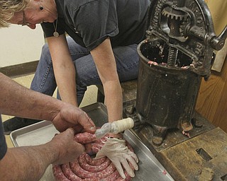 William D Lewis the Vindicator Rev Melinda Quellhorst, pastor Mt Olivet Church, North Lima, coils sausage as it comes out of a 1800',s vintage sausage machine.