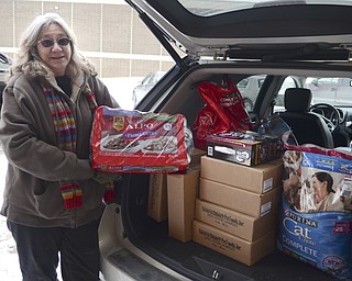 Katie Rickman | The Vindicator.Shirley Persinger of Youngstown Dogs holds donated dog food at the back of her car at Chinebox Ink on Thursday afternoon.  Aaron Chine, owner of the tattoo shop has been collecting the donated goods that was divided among 5 local animal rescues.