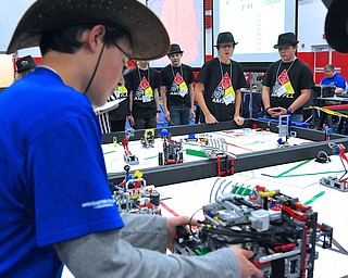 Jeff Lange | The Vindicator  AMS students Jeremy Selvy (back left), Alex Giovannone (back center) and Jacob Westmoreland (back right) of Anti-Matter look on as their robot takes on Robo-Chec from Akron (in blue), Saturday afternoon at Austintown Middle School.