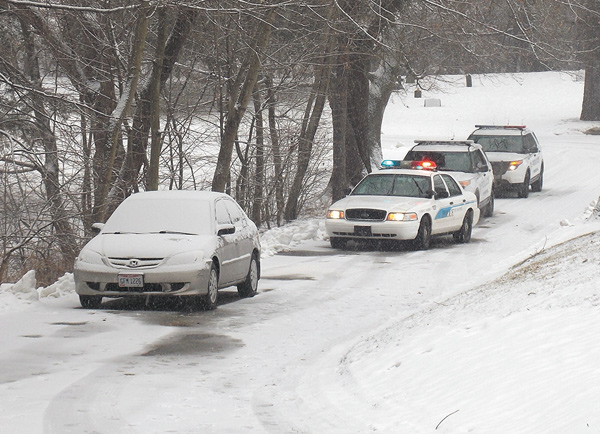 Youngstown police vehicles wait behind a car Wednesday in Calvary Cemetery that police say belonged to an elderly Oakwood Avenue man who was found dead in his home Wednesday morning.