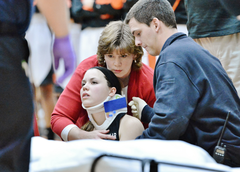 Jeff Lange | The Vindicator  Canfield's Lynne Whitehead (center) is comforted by her mother as medics prep the gurney. Whitehead was taken to the hospital after she suffered an injury to her neck and face during second half action of Canfield's game at Howland.