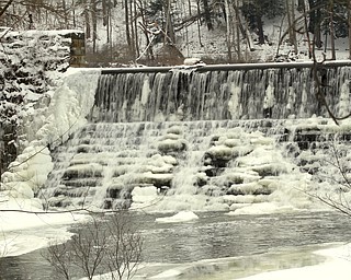        ROBERT K. YOSAY  | THE VINDICATOR..slowly as temperature falls the always cascading waters fall over the dam at Lake Cohassset ...With tempertatures hovering around zero Mill Creek Metroparks has started its annual ice show by nature as ice forms on creeks to lakes to waterfalls