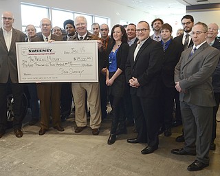 Katie Rickman | The Vindicator.Doug Sweeney (center of check) and Jim Echement who is the Director at the Rescue Mission of the Mahoning Valley pose for a photo with Sweeney Chevorlet employees and others from the Rescue Mission during the check presentation for $13,200 on Thursday, Jan. 15, 2015.