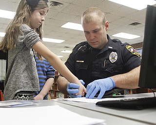        ROBERT K. YOSAY  | THE VINDICATOR..school resource officer Steve Garstka  places Cameron Dill - 4th grade fingerprints onthe form.....officer as part of a PTA/School/ and Canfield PD initiative... students in k-4 in the Canfield Schools will have an Identity Kit done in school with their fingerprints and then sent home to the parents.