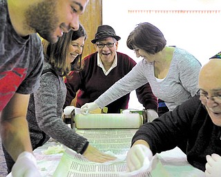 Neil Yutkin, at end of table, chairman of the ritual committee at Congregation Ohev Tzedek in Boardman, unrolls the Torah as volunteers begin wiping it down. From left are Josh Ford, Debbie Tosi, Linda Davis and Jim Smythe. Cleaning the Torahs is a special project at the synagogue. This Torah is about 125 years old.