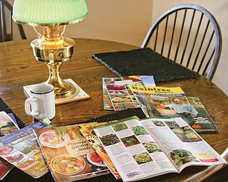 A kitchen table with a variety of seed catalogs. A good activity for a snow day is to start ordering seeds and plants for your spring garden.