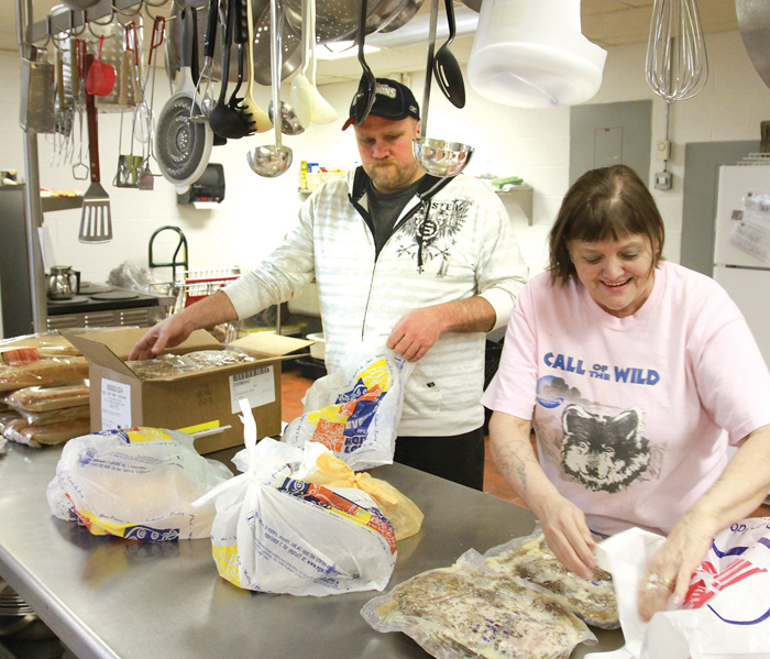Volunteers Tim Wilson of Vienna and Sharon Steed of Warren sort frozen foods during a food give away at Pleasant Valley Church in Liberty.
