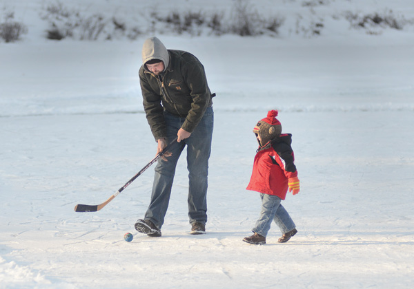 Tre’ Black entertains his son Case, 2, while his other son plays hockey on the Lily Pond in Mill Creek Park. The pond opened for ice skating Friday and will be open through the end of the month. This is the second year since 1990 that conditions have allowed the park administration to open the pond for skating.