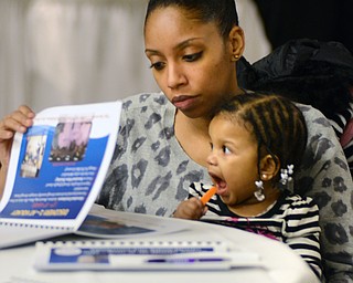 Katie Rickman | The Vindicator.Jade Jackson of Youngstown holds her one-year-old daughter Mariah Jamison and reads through a handout prior to the  2015 State of the District Address  at Our Lady of Mount Carmel Church on Thursday, Jan. 22, 2015.