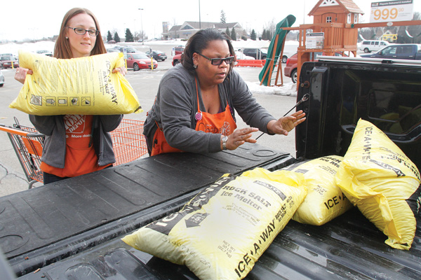 Home Depot employees Jeannie Mottram and Cherrie Childs load salt into Linda Reed’s truck Tuesday afternoon in Austintown.