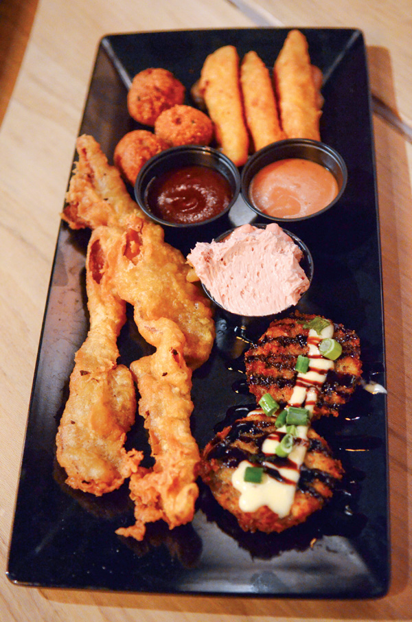 A sample platter featuring a little bit of everything from the appetizer menu at Fire Grill in Girard. Featured on platter: fried green tomatos, pigs in a basket (deep fried battered bacon) Hushpuppies, and Frickled Pickles (dill pickles deep fried).
