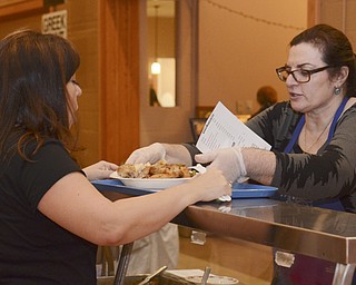 Katie Rickman | The Vindicator.Penelop (OKAY) Hazimihalas of Campbell (on right) serves traditional Greek food to Georgienne Douropoulos of North Lima during the first night of the Greek Festival at Archangel Michael Greek Orthodox Church in Campbell on Friday, Feb. 13, 2015.
