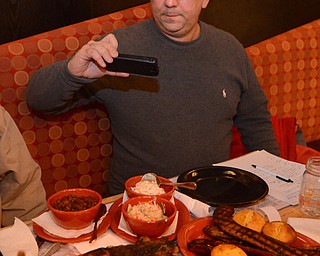 Katie Rickman | The Vindicator .Mark Smesko takes a photo of one of the signature dishes at Fire Grill in Girard on Thursday, Jan. 29, 2015.