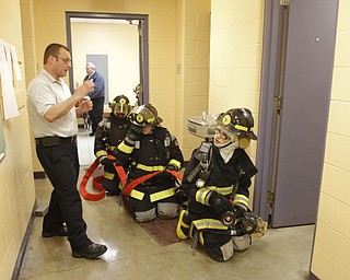        ROBERT K. YOSAY  | THE VINDICATOR..Capt Fred Beehler instructor and YFD  teaches Rick Alli (front with nozzle and Kristen Bowman how to feel for heat before opening a door...A new program at Choffin Career and Technical Center teaches students fire fighting skills and techniques while aiming to increase the number of Youngstown residents in the fire department ranks..