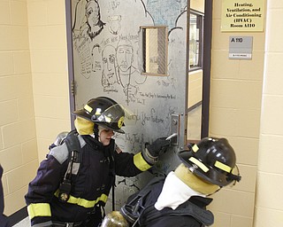        ROBERT K. YOSAY  | THE VINDICATOR..Capt  Jim Sapp instructor and YFD  teaches Rick Alli (front with nozzle and Kristen Bowman how to feel for heat before opening a door...A new program at Choffin Career and Technical Center teaches students fire fighting skills and techniques while aiming to increase the number of Youngstown residents in the fire department ranks..