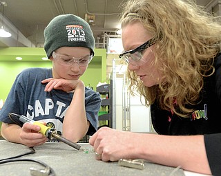 Jeff Lange | The Vindicator  Richard Blair (11) of Youngstown (left) gets assistance soldering a wire onto lights from Oh Wow! volunteer Audra Carlson, Saturday afternoon during a flashlight building activity at Oh Wow Children's Center for Science and Technology.