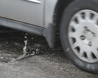        ROBERT K. YOSAY  | THE VINDICATOR..Pot Hole Season came early as hard freezes combined with thaws have got area roads.. full of the driving hazards ..water and debris fly out of a hole on Market Street near Cleveland in Northbound lanes . .-30-