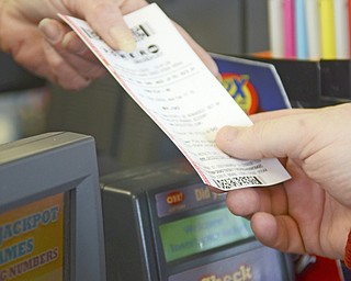 Katie Rickman | The Vindicator.A gas station attendant hands a Powerball ticket to a customer at  Country Fair gas station in Boardman on Wednesday, Feb. 11, 2015.