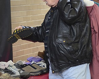 Katie Rickman | The Vindicator.Ed Baumgartner of Youngstown holds up a sandle and looks at it while holding coats over his shoulder at the Salvation Army in Youngstown on Wednesday, Feb. 11, 2015. Ankle and Foot Center donated over 500 pairs of shoes to the Salvation Army.