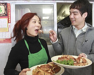 William D Lewis The Vindicator  Sue Zhang, owner of Girard Wok gets a sample of a Chinese New Year dish from her son Gene Huang.