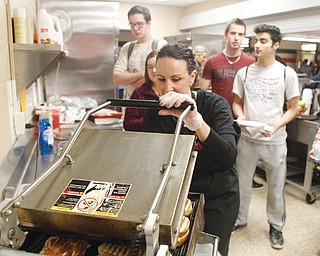 Barb Cummings, who some in the district just know as “the Panini Lady,” works the panini press during lunchtime at Canfield High School. Students stand and talk as the sandwiches cook for 60 seconds.