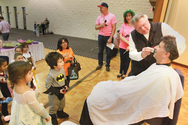 Tom Borocz of Girard, a professional barber, shaves off Mark Perlman’s mustache that he’s had for 44 years during the Purim Extravaganza on Wednesday night at Temple El Emeth in Liberty. The “Slash the Stache” event was a fundraiser for the temple. Also on the stage are Elyse Silverman, program and education director at the temple, and Steve Stoyak, master of ceremonies.