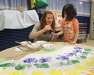        ROBERT K. YOSAY  | THE VINDICATOR..Poland Union Elementary pre school program .. will be expanded and moved to Poland North - Next school year .Megan Harwell  paints the hand of Adriana Sause - as they make  a rainbow of hands..