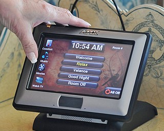 Jeff Lange | The Vindicator  Owner and innkeeper of the Sebring Mansioin Inn & Spa, Lynne Biery demonstrates how the Interactive HomeWorks system is used to adjust the brightness of the lights in the room. From that tablet, one can also adjust room temperature and control the television.