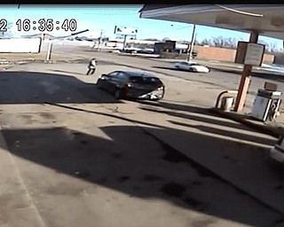 Photograph from the surveillance video of a West Market Street gas station shows a white car passing a gas station at 4:35 p.m. just ahead of a cloud of dust.