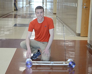 Katie Rickman | The Vindicator.Caleb Spalding, a senior at Jackson-Milton High School  kneels next to a a mouse trap racer that he designed in a physics class at the school, it won an award at a pysics competition.