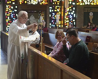 Katie Rickman | The Vindicator.Richie Wozniak of Hubbard makes the sign of the cross as his mother Paula Wozniak watches as Rev. Timothy O'Neill blesses them during the Easter Basket Blessing Ceremony at St. Patricks Church in Hubbard on April 4, 2015.