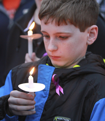 William D Lewis The vindicator Joseph Mullarkey, 11, of Youngstown holds a candle during a 4-7-15 vigil for 3 people who died in a Youngstown house fire.