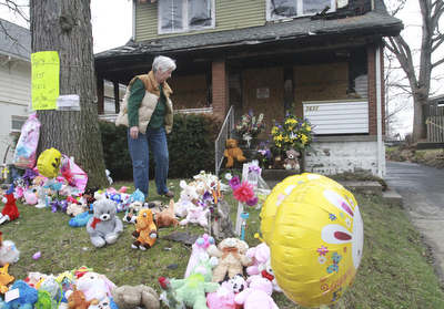 84 year old Jean McCammon arranges items ina memorialto fire victims killed in a Pwers way fire in Youngsotwn. She is a neighbor and was an eyewitness to the fire.