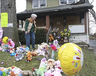84 year old Jean McCammon arranges items ina memorialto fire victims killed in a Pwers way fire in Youngsotwn. She is a neighbor and was an eyewitness to the fire.