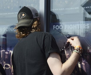 Katie Rickman | The Vindicator .Jack Grbac of Cleveland tries to catch a glimpse of the inside of the building in the Pine Tree Place Shopping Center in Niles  the Foo Fighters played for 150 fans.  The Foo Fighters performed in honor of National Record Store Day.