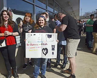 Katie Rickman | The Vindicator .Amy Ronyak of Warren, center, holds a homemade sign and stands in line at the Pine Tree Place Shopping Center in Niles while waiting for the doors to open for the Foo Fighters Concert.  The Foo Fighters performed in honor of National Record Store Day.