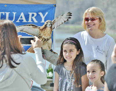 Jeff Lange | The Vindicator  APRIL 18, 2015 - Natalia Santiago, age 9, and her cousin Genevieve Macejko, age 6, pose with Rain the red-tailed hawk and Birds In Flight Sanctuary's Heather Merritt (top right) as their grandmother Margarita Santiago of Campbell snaps a photo, Saturday at Fellows Riverside Gardens in Youngstown during the 9th annual Children's Book Festival.