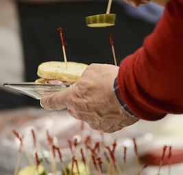 Katie Rickman | The Vindicator.A man holds a sandwich in one hand and picks up a pickle, adding it to his plate during the Memorable Meals Mahoning Valley at the Stambaugh Auditorium on April 26, 2015.