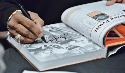 Jeff Lange | The Vindicator  APRIL 25, 2015 - 5-time Pro Bowl running back and former Cleveland Brown, Greg Pruitt, autographs a page in a book for a fan during Saturday's meet and greet at Firebirds in Niles.