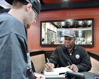 Jeff Lange | The Vindicator  APRIL 25, 2015 - 5-time Pro Bowl running back and former Cleveland Brown, Greg Pruitt, signs the page of a book for Warren resident Eric Ferringer during Saturday's autograph signing at Firebirds in Niles.