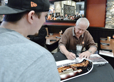 Jeff Lange | The Vindicator  APRIL 25, 2015 - Kicker for the 1980 Cleveland Browns Don Cockroft (right) signs a poster of the old Cleveland Municipal Stadium, site of the first Monday Night Football game in 1970 for Anthony Goett of Warren, Saturday afternoon at Firebirds Grill in Niles.