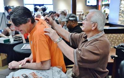 Jeff Lange | The Vindicator  APRIL 25, 2015 - Kicker for the 1980 Browns Don Cockroft (right) signs the back of Robert Stevens of Warren during Saturday afternoon's autograph signing at Firebirds.